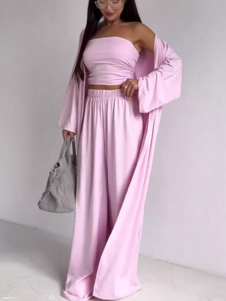 Blush pink three-piece maternity set with ruched bandeau crop top, wide-leg pants, and open cardigan.