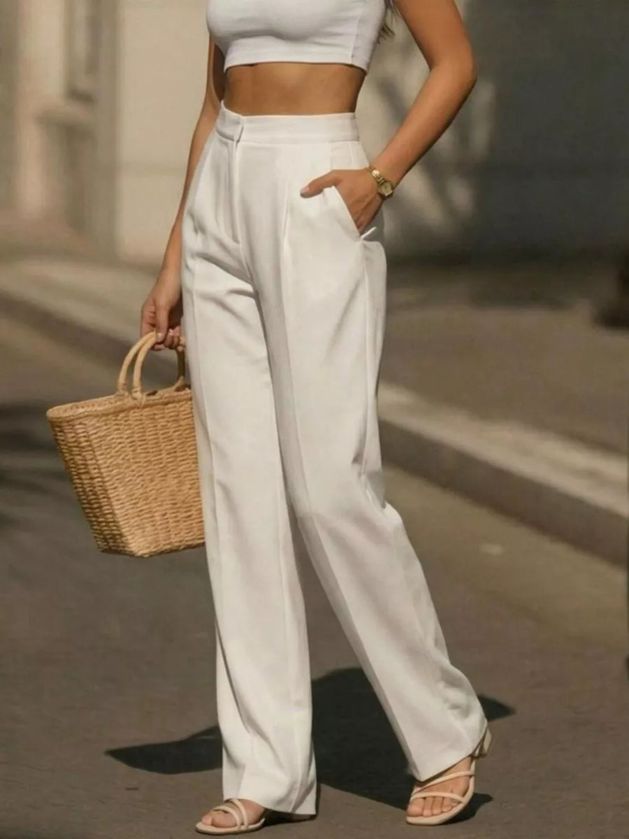 White high-waisted wide-leg trousers with a tailored fit and pockets, styled with a crop top and sandals.