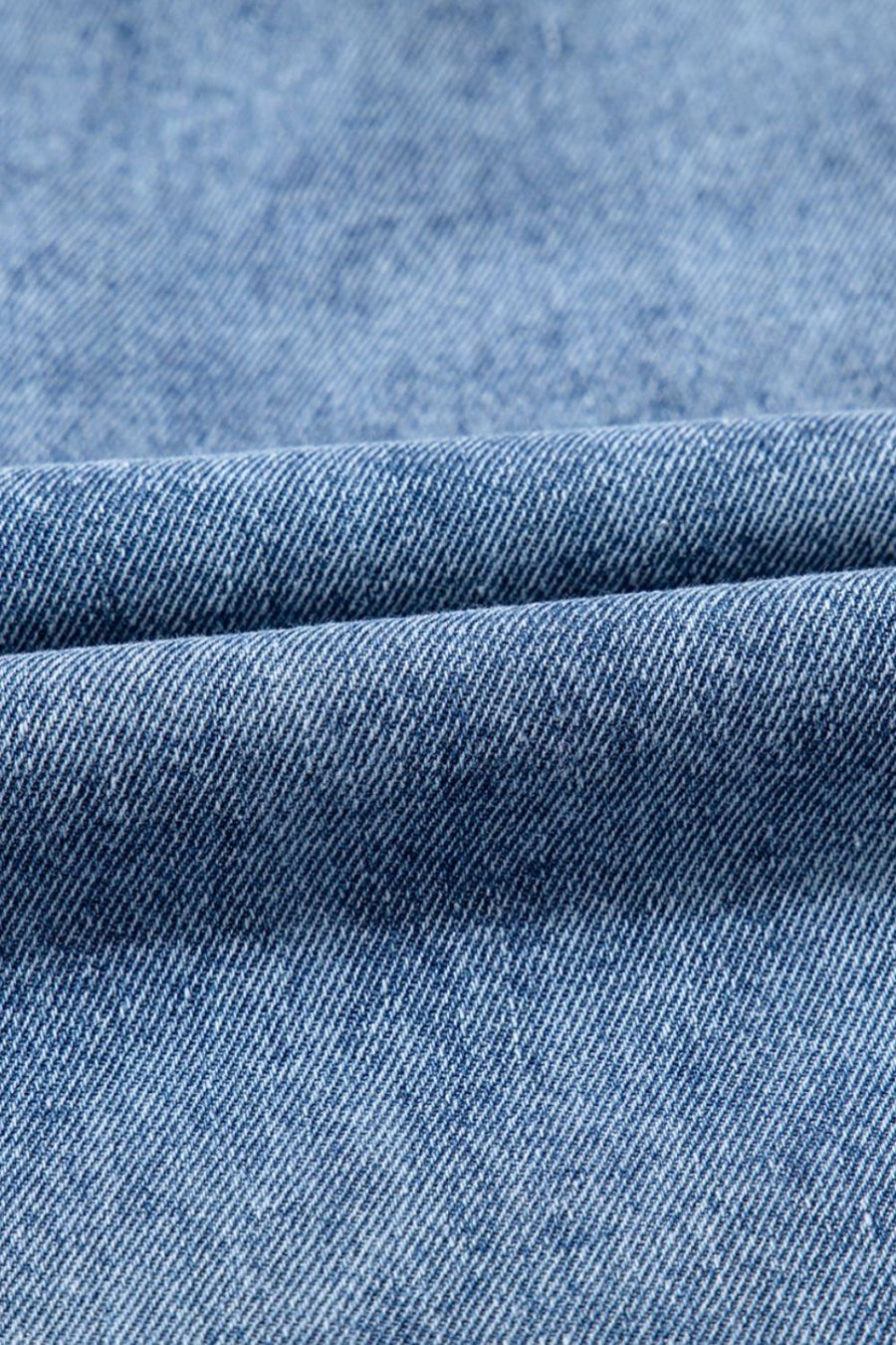 Utility denim mini dress in light blue, showing fabric texture and fold detail.