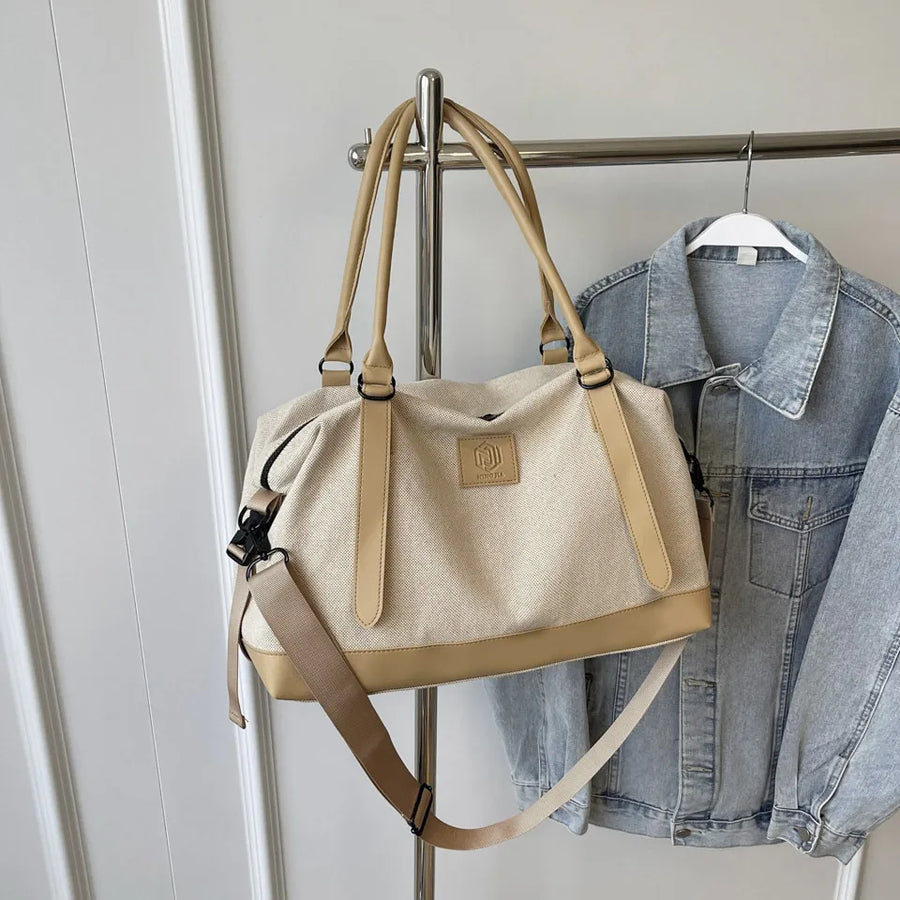 Canvas weekend holdall duffel bag in beige with tan accents and adjustable strap.