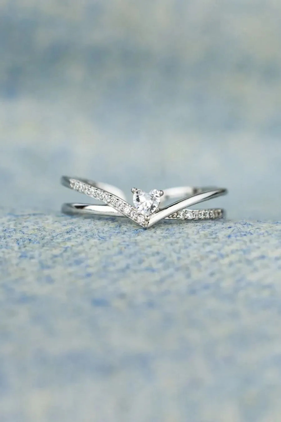Silver V-shaped ring with diamond accents and a heart-shaped center stone.