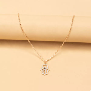Gold evil eye hamsa pendant necklace with clear rhinestones and black eye detail.