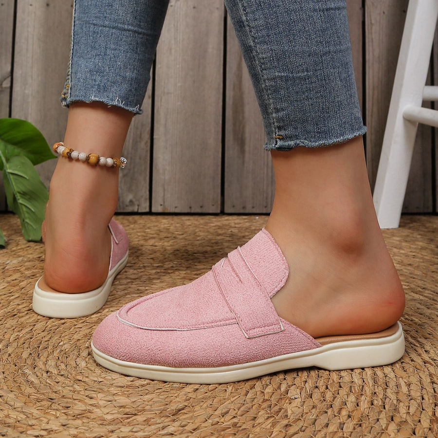 Pink textured round toe slip-on loafers with a backless design and decorative strap detail.