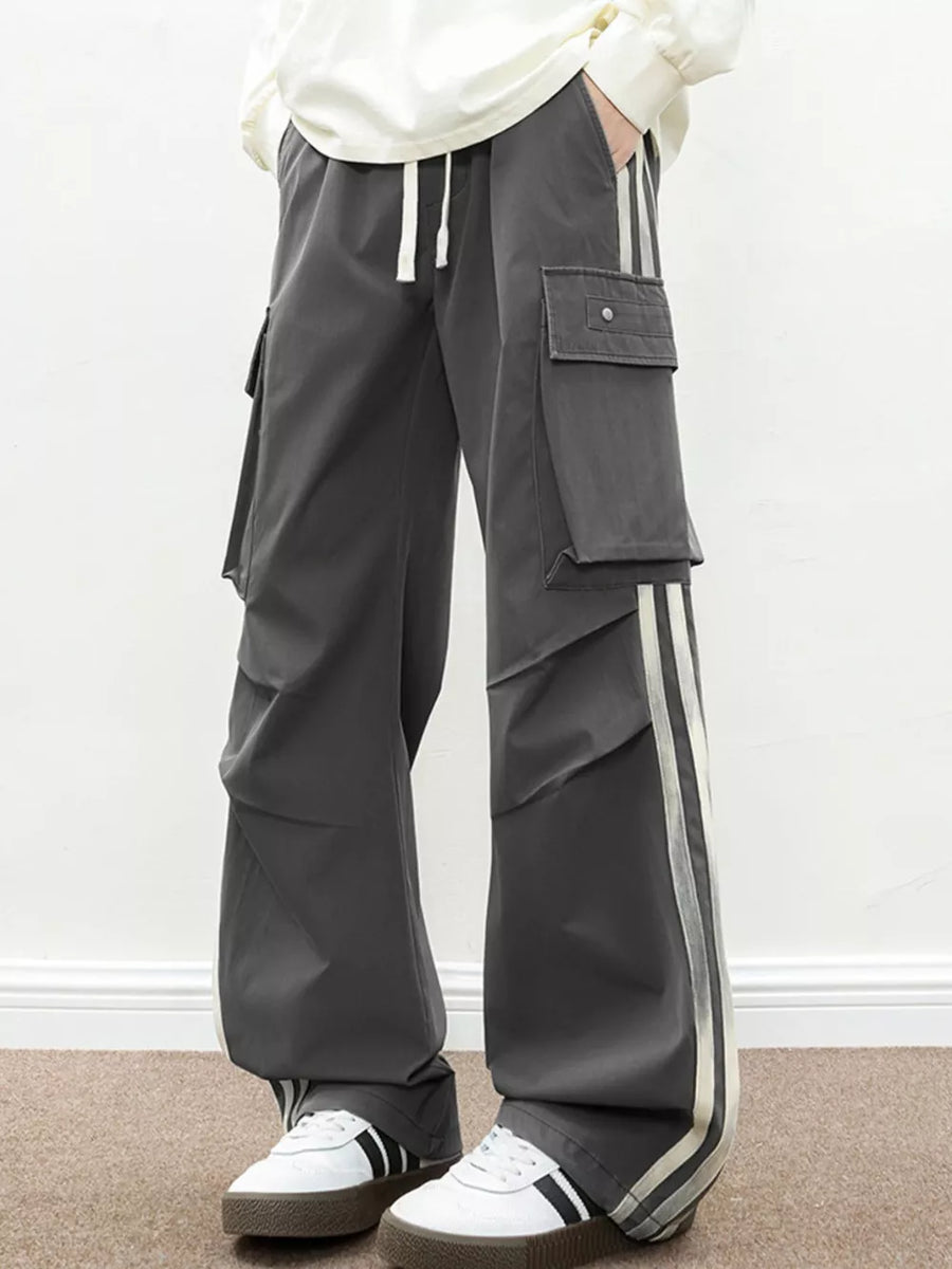Oversized dark gray cargo pants with flap pockets and side stripes.