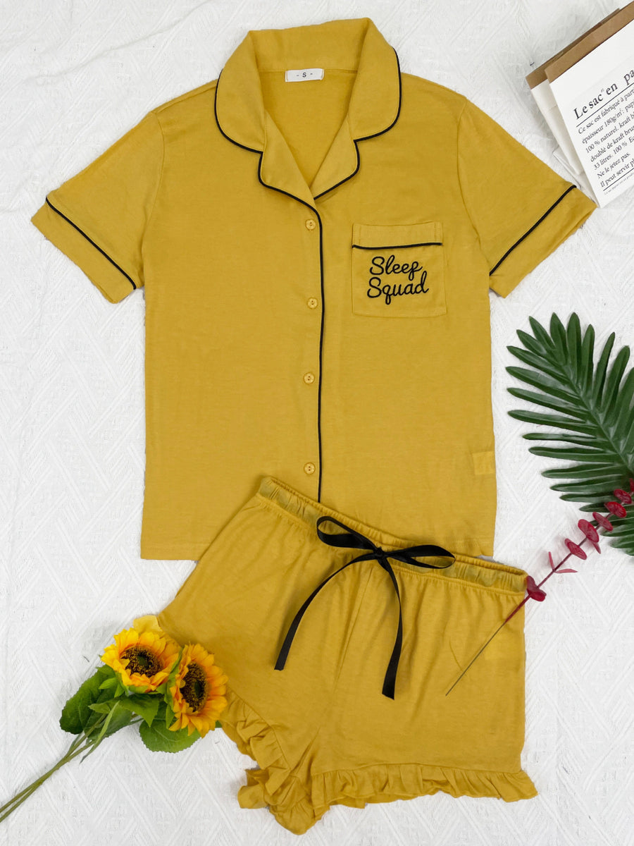 Yellow pajama set with black trim, short sleeves, and ruffled shorts.