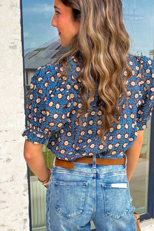 Blue floral cotton blouse with puff sleeves and ruffled cuffs.