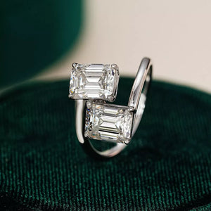 Emerald-cut moissanite bypass ring in silver with two radiant stones.