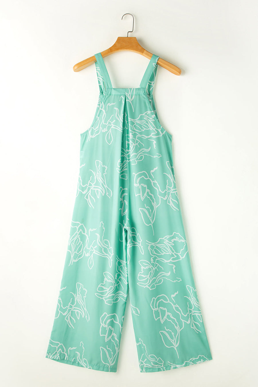 Turquoise botanical print wide-leg jumpsuit with wide straps and pleats.