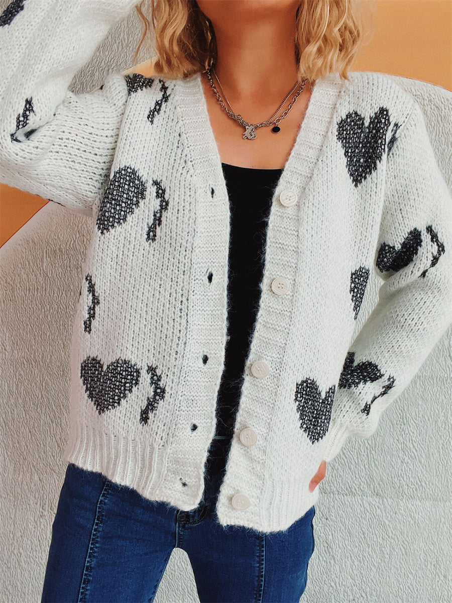 White knit cardigan with black heart motif, button front, V-neck, long sleeves.