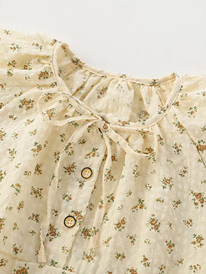 Cream floral cotton dress with puff sleeves, button front, and tie neck.