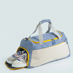 Colorblock duffel bag in dusty blue and beige with yellow trim, featuring a shoe compartment with sneakers.