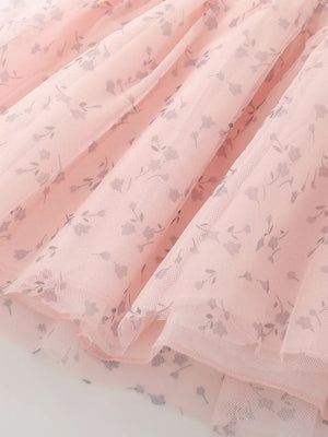 Blush pink tulle baby dress with a delicate floral print and layered skirt detail.