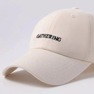 Beige cotton baseball cap with embroidered "GATHERING" text detail.