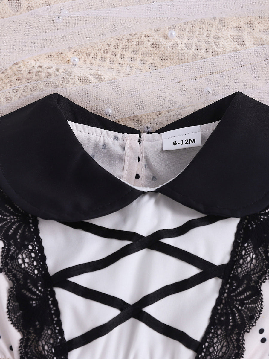 Baby dress with black collar, lace trim, criss-cross ribbon detail, and polka dot pattern.