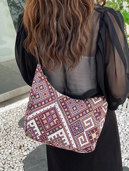 Embroidered geometric hobo bag in burgundy with colorful stitching and a casual slouchy style.