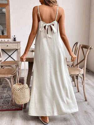 Maxi dress with adjustable spaghetti straps and a back bow detail in a light neutral color.