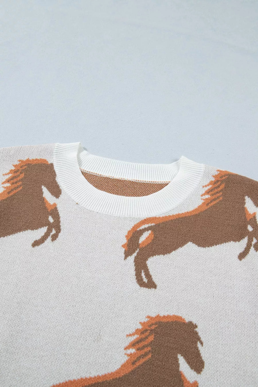 White knit sweater with brown horse print and crew neck.
