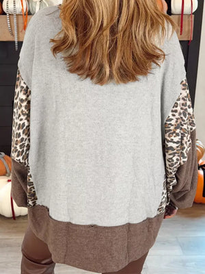 Leopard print graphic sweatshirt with grey body and brown hem.
