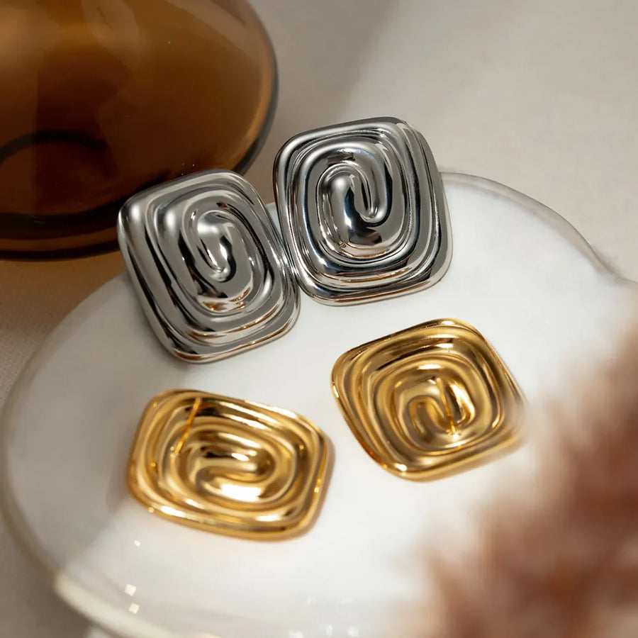 Sculpted swirl square earrings in gold and silver feature a contemporary, chic design.