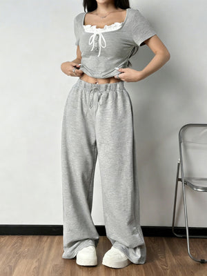 Grey tie-front cropped top with ruffled neckline and drawstring wide-leg pants set.