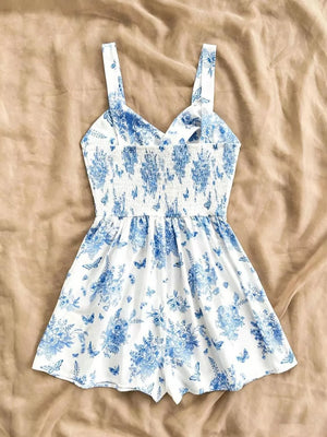 White and blue floral print romper with smocked waist and butterfly details.