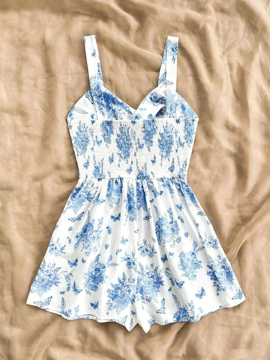White and blue floral print romper with smocked waist and butterfly details.