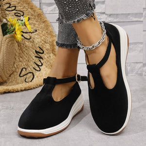 Black T-bar flat slip-ons with adjustable ankle strap and white platform sole.