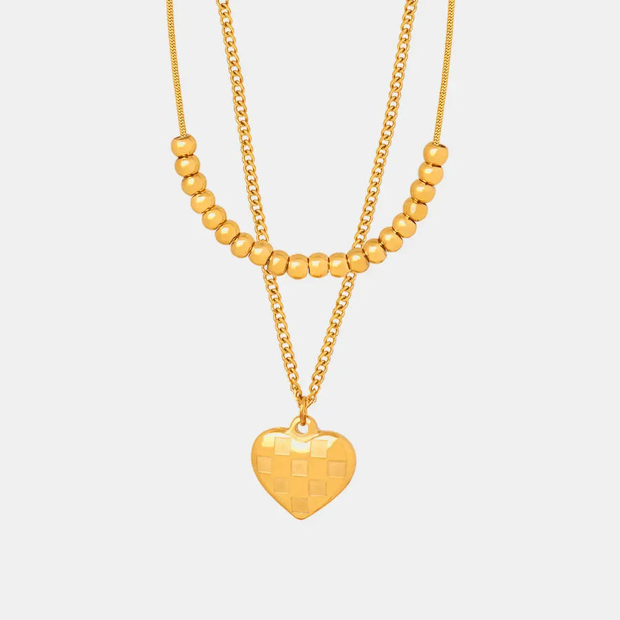 Gold layered necklace with beaded chains and a checkered heart charm.