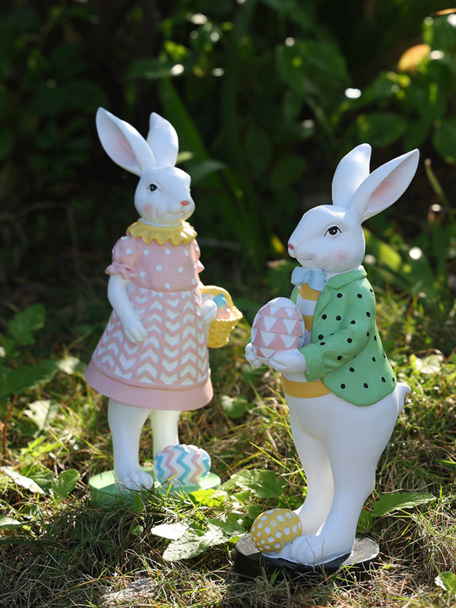 Easter bunny figurines in pink and green outfits holding decorative eggs and baskets.