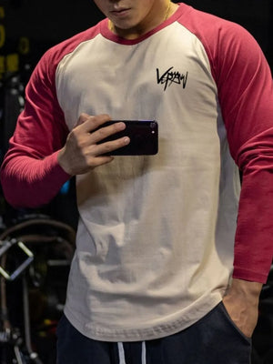 Raglan sleeve graphic tee in beige with deep red sleeves and a black graphic logo.