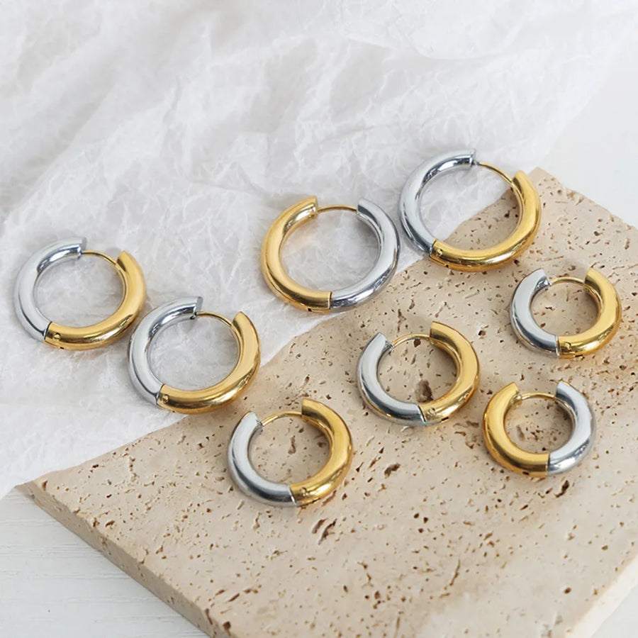 Two-tone segmented hoop earrings in gold and silver metal.