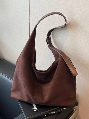 Brown suede hobo bag with adjustable leather strap and silver buckle detail.
