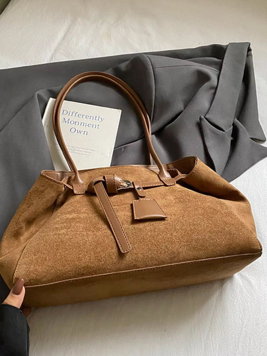 Women's chic brown suede shoulder bag with leather trim and buckle detail.