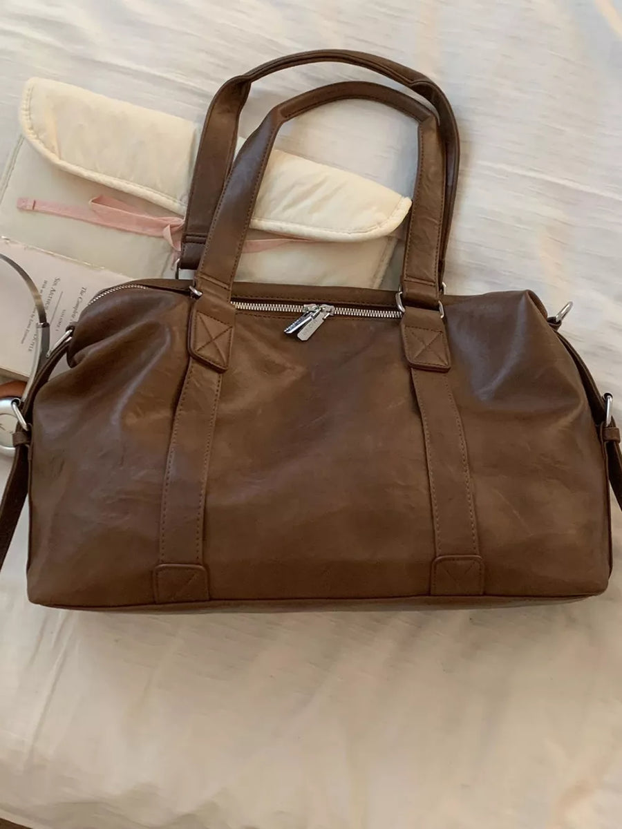 Brown pu leather shoulder bag with double handles and a charm detail.