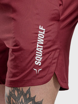 Burgundy performance shorts with split hem and white logo detail