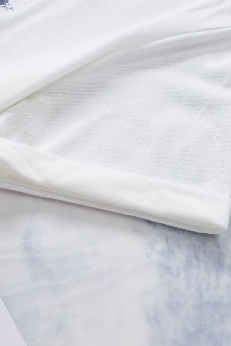 White graphic tee with floral accents and rolled sleeves.
