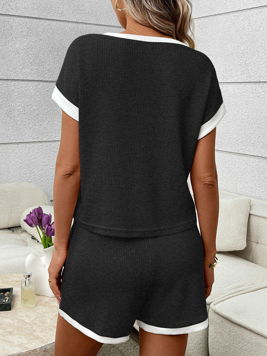 Black ribbed knit two-piece set with white trim, short sleeves, and shorts.