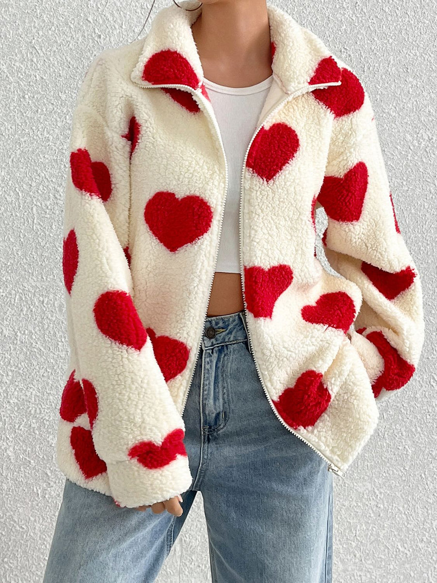 White sherpa zip-up jacket with red heart print and a collared neckline.
