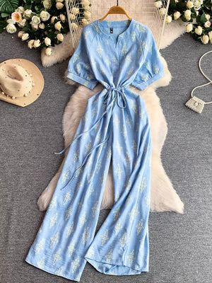Blue floral print drawstring jumpsuit with short sleeves and wide legs.