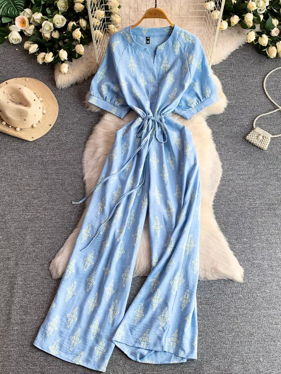 Blue floral print drawstring jumpsuit with short sleeves and wide legs.