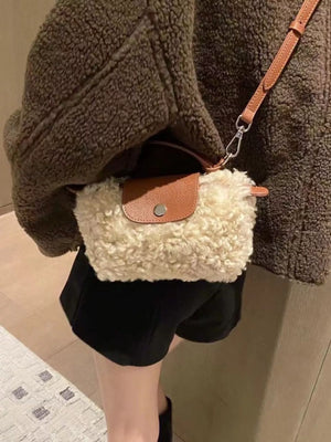 Textured mini crossbody bag in cream sherpa with brown leather flap and strap.