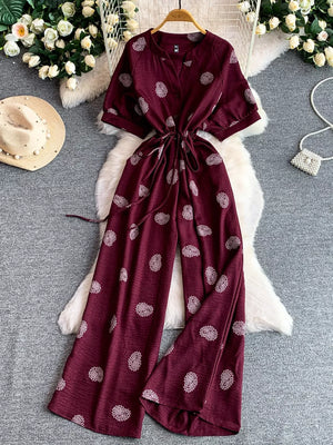 Burgundy patterned drawstring jumpsuit with short sleeves and wide legs.