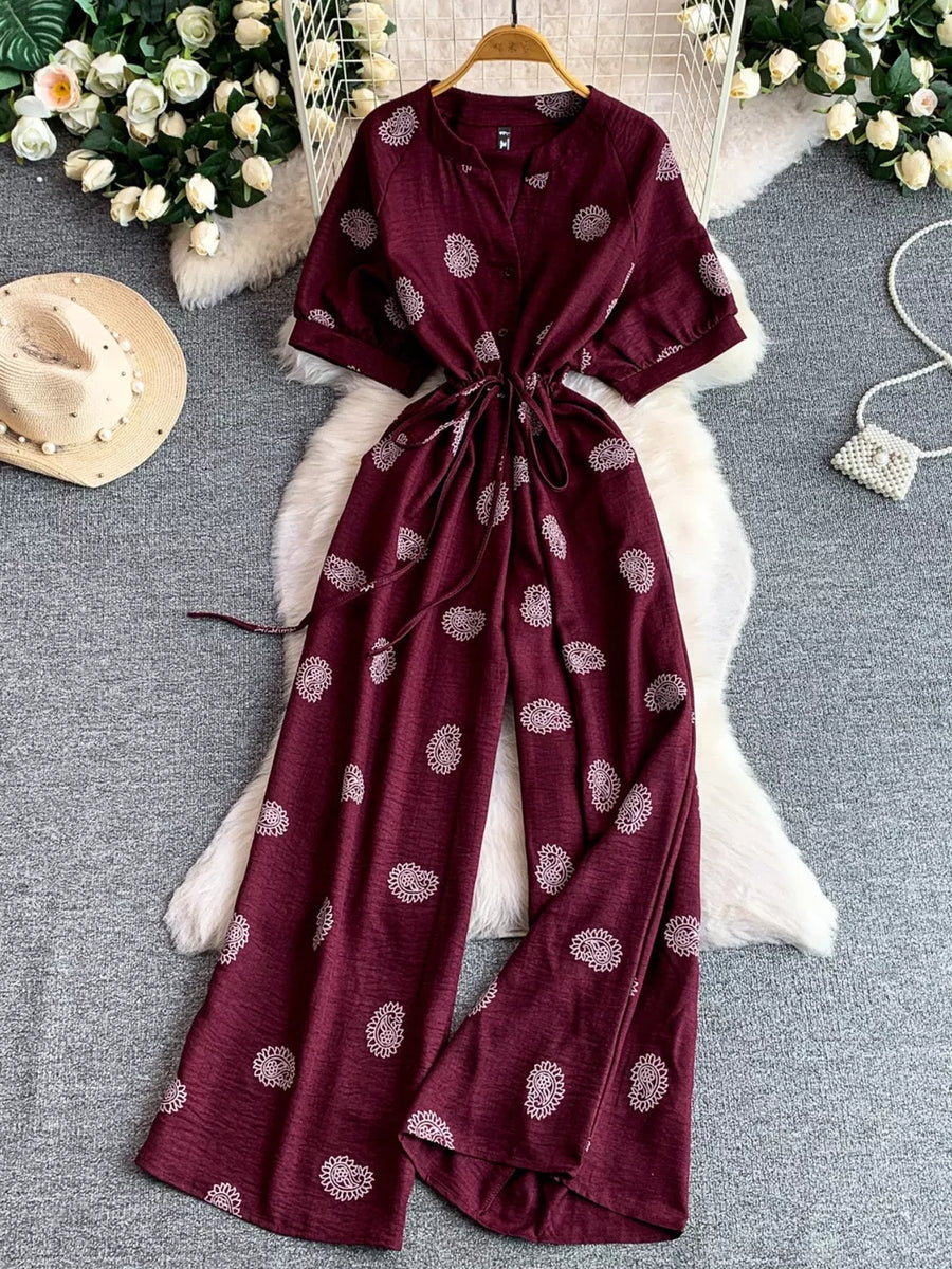 Burgundy patterned drawstring jumpsuit with short sleeves and wide legs.