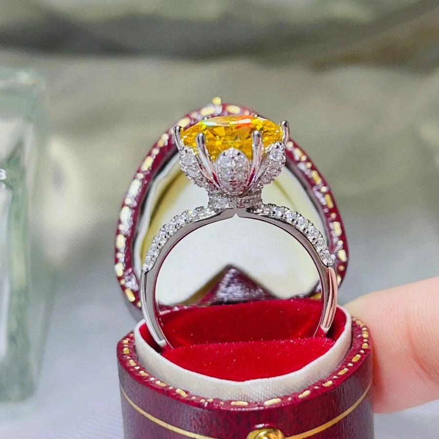 Yellow moissanite solitaire ring with diamond halo and band in a ring box.