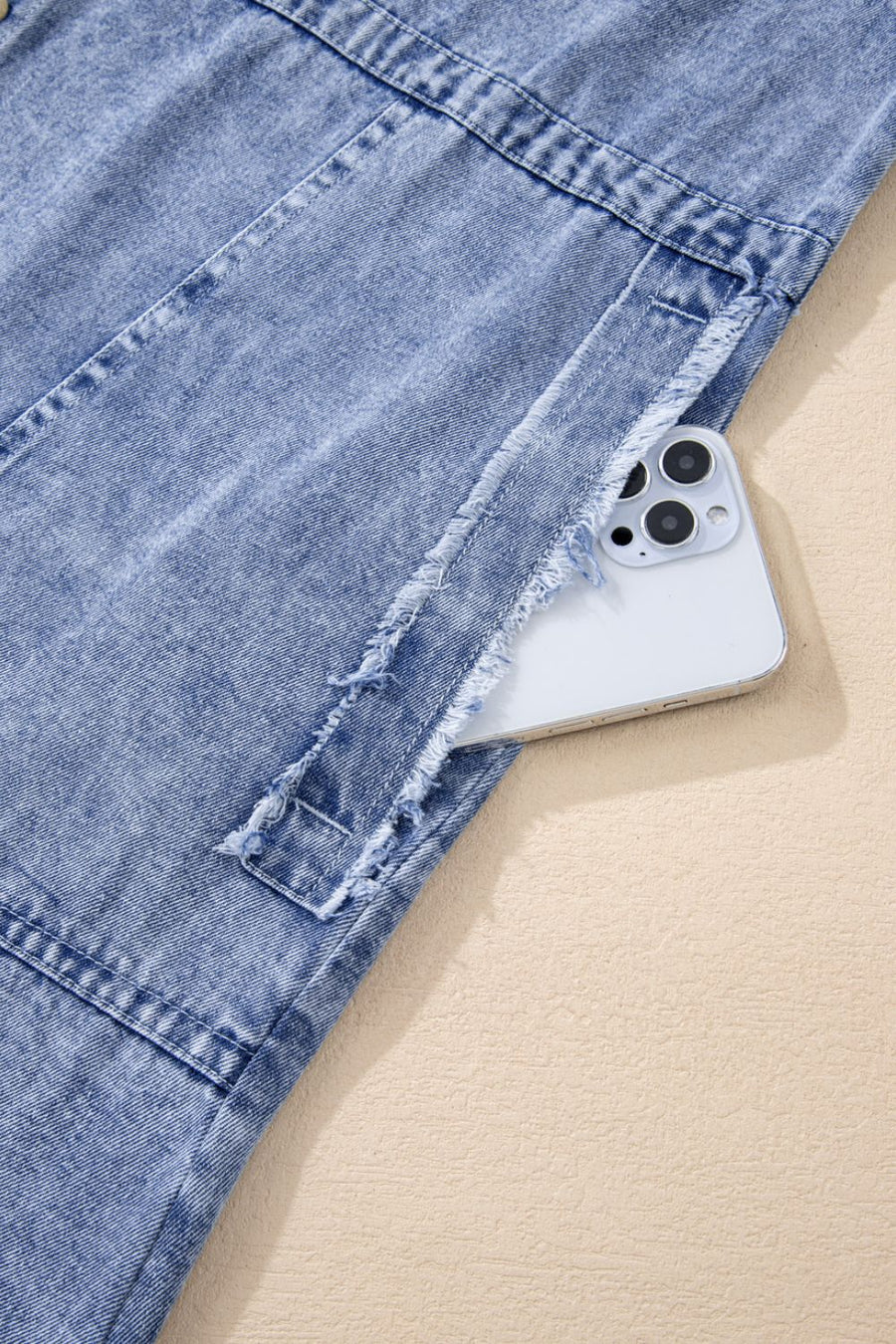 Acid wash denim shirtdress with raw hem detail and pocket holding a phone.