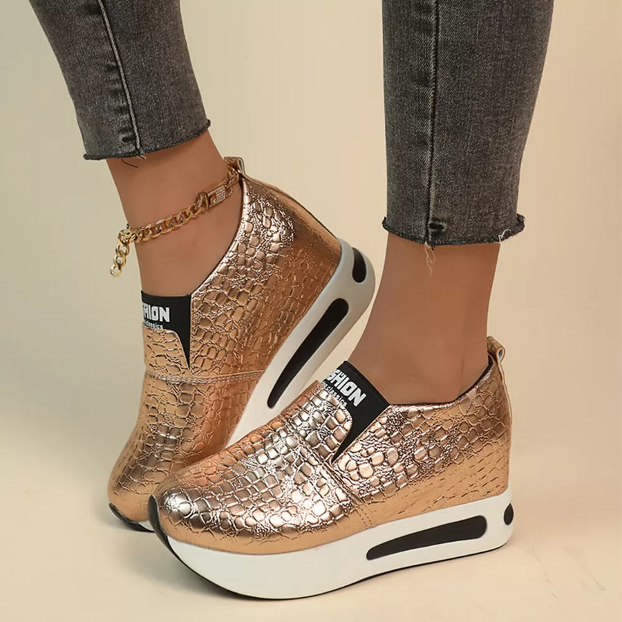 Gold crocodile-embossed platform sneakers with chunky white soles and a gold chain anklet.