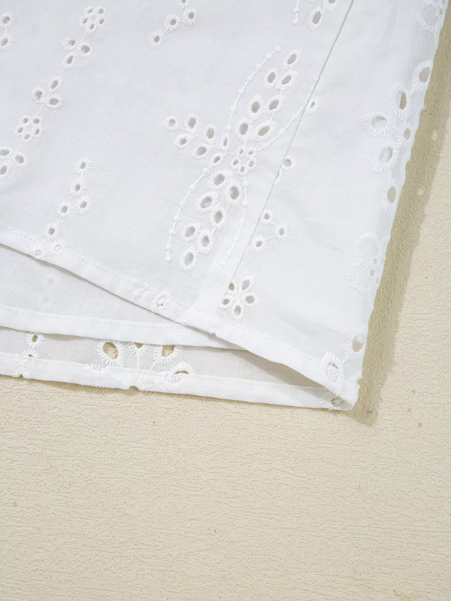 White cotton maternity blouse with delicate eyelet embroidery and ruffled details.
