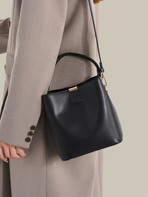 crossbody bag in black featuring gold-tone hardware and bucket fit