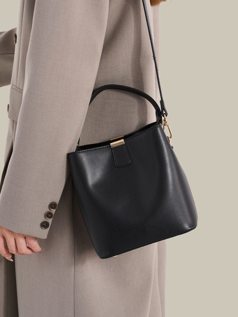 crossbody bag in black featuring gold-tone hardware and bucket fit