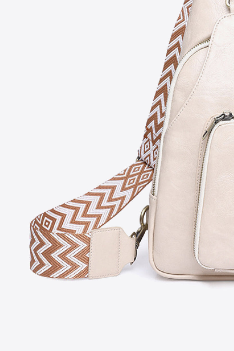 Ivory PU sling bag with a patterned strap and zipper detail